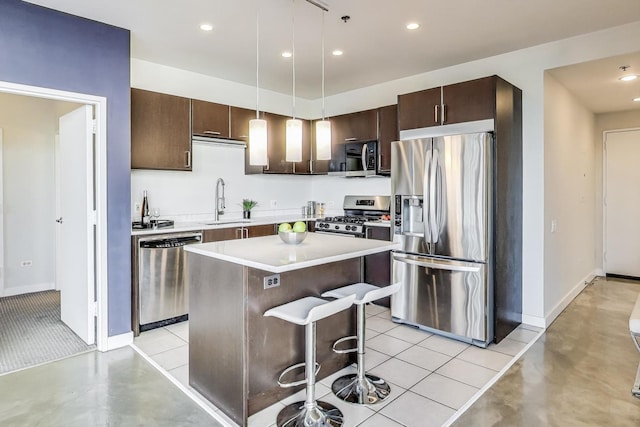 kitchen with sink, a breakfast bar area, decorative light fixtures, a kitchen island, and stainless steel appliances