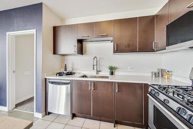 kitchen featuring appliances with stainless steel finishes, sink, light tile patterned floors, and dark brown cabinets