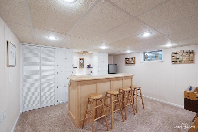 kitchen featuring a breakfast bar area, light colored carpet, and stainless steel fridge