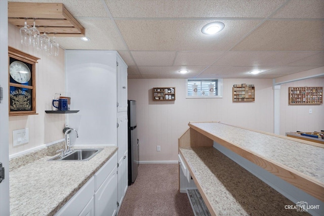 bar featuring sink, stainless steel refrigerator, white cabinetry, light stone countertops, and dark carpet