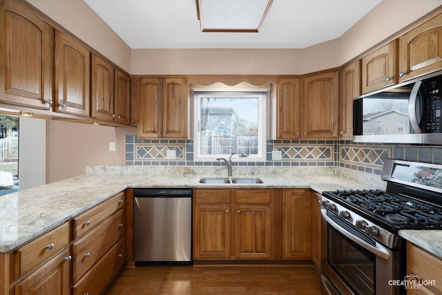 kitchen with dark hardwood / wood-style floors, decorative backsplash, sink, appliances with stainless steel finishes, and light stone counters