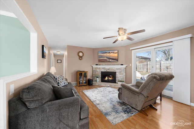 living room featuring ceiling fan, hardwood / wood-style floors, and a fireplace