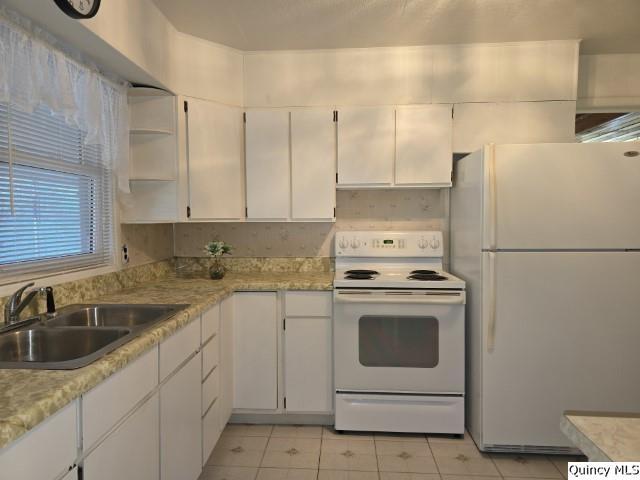 kitchen with white cabinetry, sink, light tile patterned floors, and white appliances