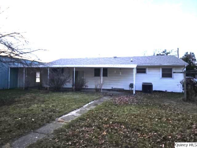 back of property with central AC and a lawn