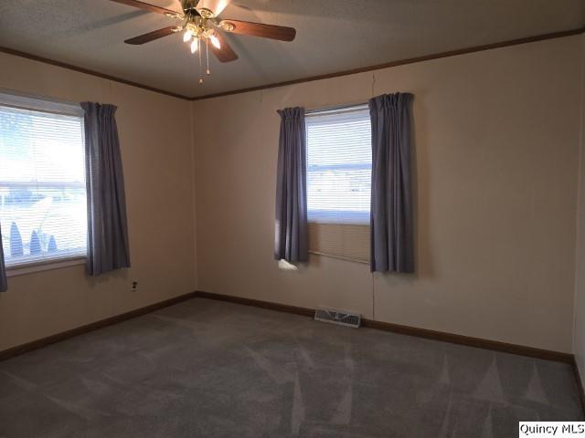 carpeted empty room with crown molding and ceiling fan