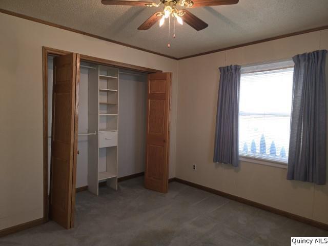 unfurnished bedroom with ornamental molding, carpet floors, ceiling fan, and a textured ceiling