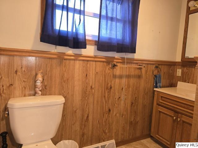 bathroom with vanity, toilet, and wood walls