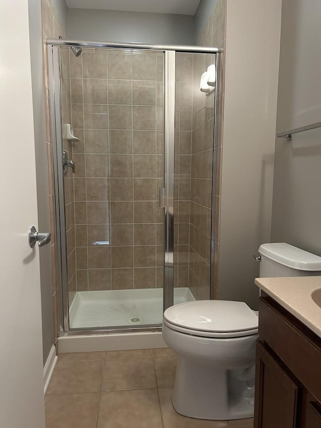 bathroom with vanity, a shower with shower door, tile patterned floors, and toilet