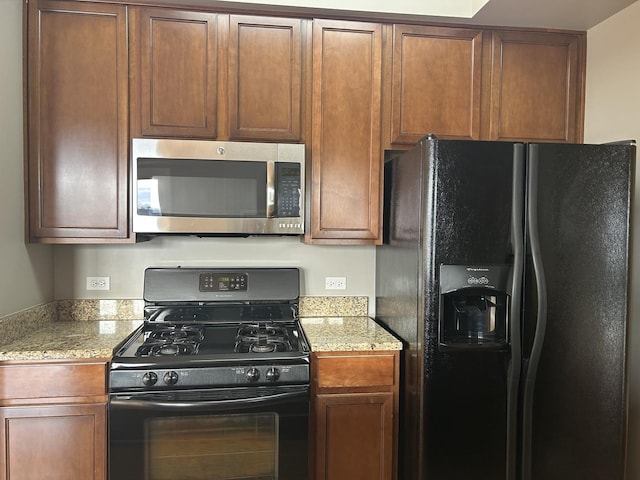 kitchen featuring black appliances and light stone counters