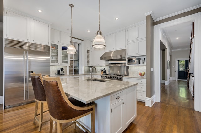 kitchen with backsplash, sink, stainless steel built in fridge, a kitchen breakfast bar, and an island with sink