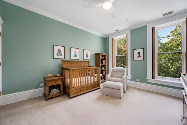 carpeted bedroom featuring ceiling fan, a nursery area, and ornamental molding