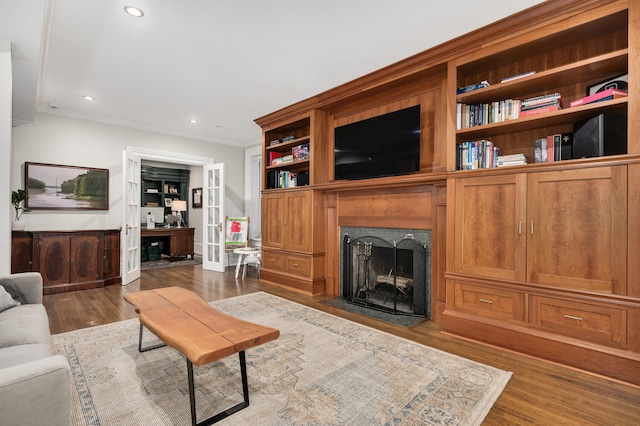 living room featuring crown molding, built in features, and hardwood / wood-style floors