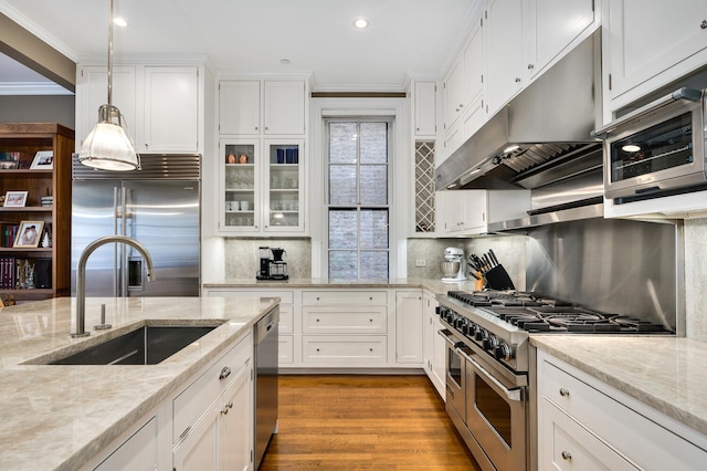 kitchen featuring pendant lighting, sink, premium appliances, and white cabinetry