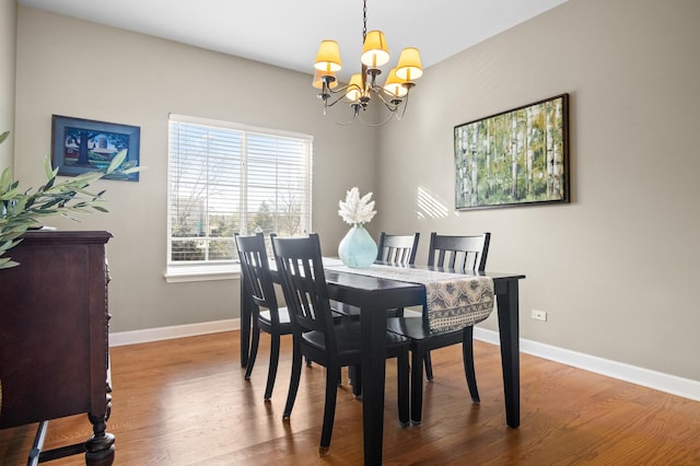 dining space with hardwood / wood-style flooring and an inviting chandelier