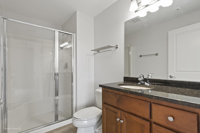 bathroom featuring toilet, vanity, tile patterned flooring, and a shower with door