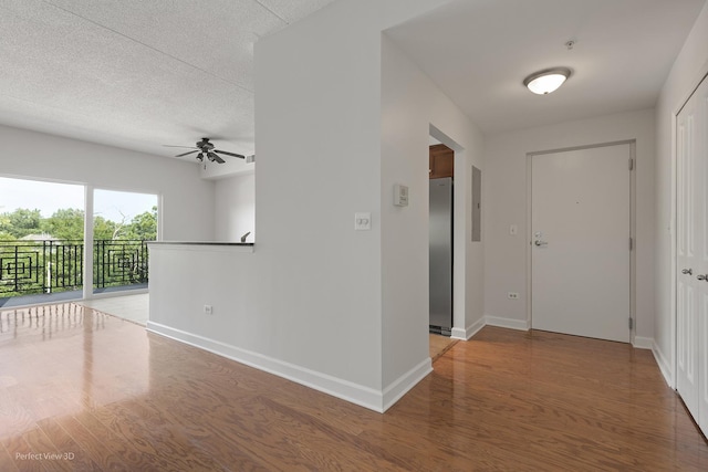 hall with a textured ceiling, electric panel, and wood-type flooring