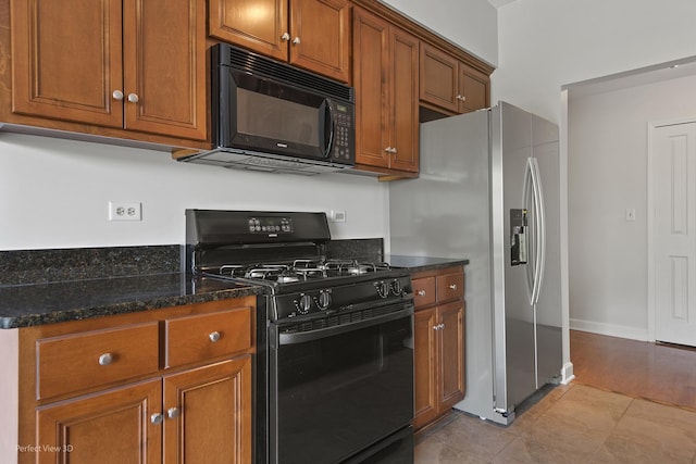 kitchen featuring light tile patterned floors, black appliances, and dark stone counters