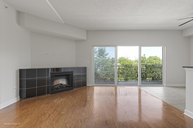 unfurnished living room featuring a textured ceiling, wood-type flooring, and a tile fireplace