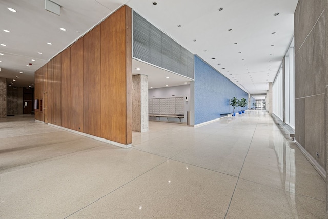 corridor featuring wooden walls and a high ceiling