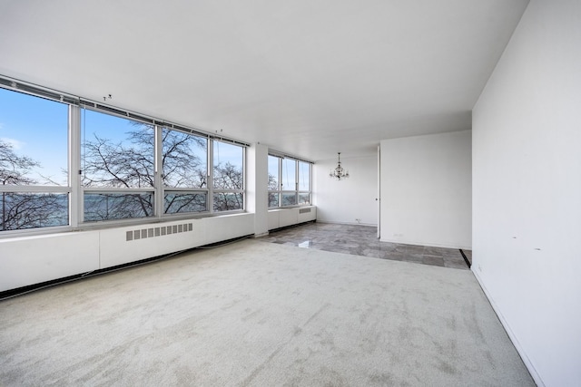 empty room featuring a chandelier and carpet floors