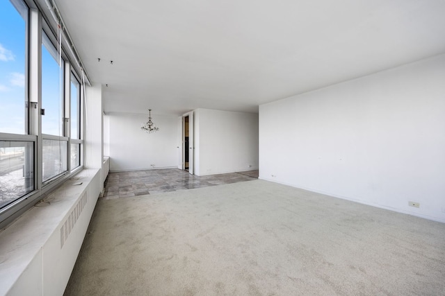 carpeted empty room featuring a chandelier