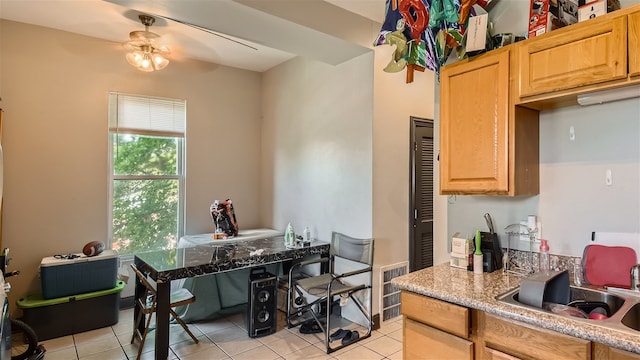 kitchen featuring ceiling fan, light tile patterned floors, light brown cabinetry, and sink