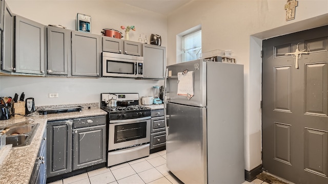 kitchen with light tile patterned floors, appliances with stainless steel finishes, gray cabinetry, and sink