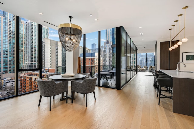 dining space with an inviting chandelier, sink, light hardwood / wood-style floors, and expansive windows