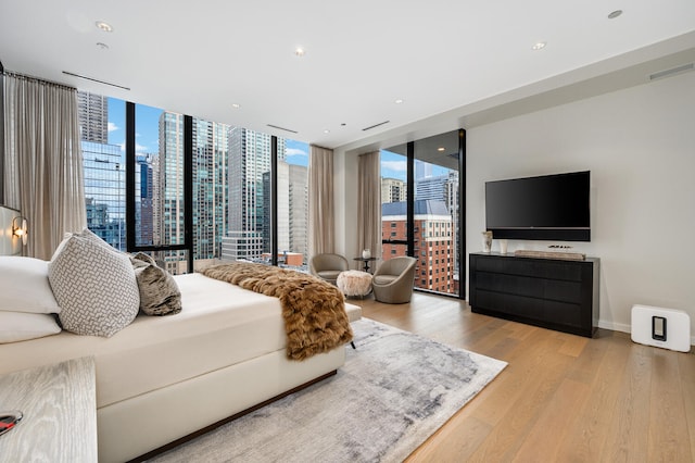 bedroom featuring access to outside, floor to ceiling windows, and light wood-type flooring