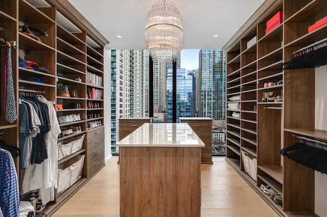 walk in closet with a notable chandelier and light hardwood / wood-style flooring