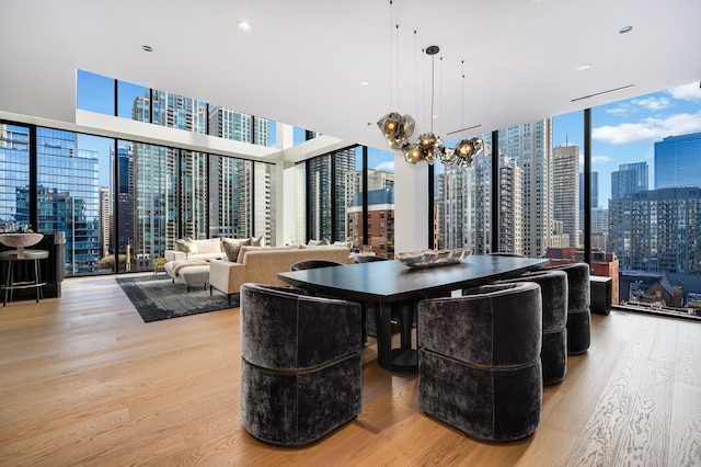 dining area with an inviting chandelier, expansive windows, and light hardwood / wood-style flooring