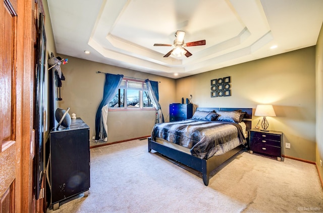 bedroom with a tray ceiling, light colored carpet, and ceiling fan