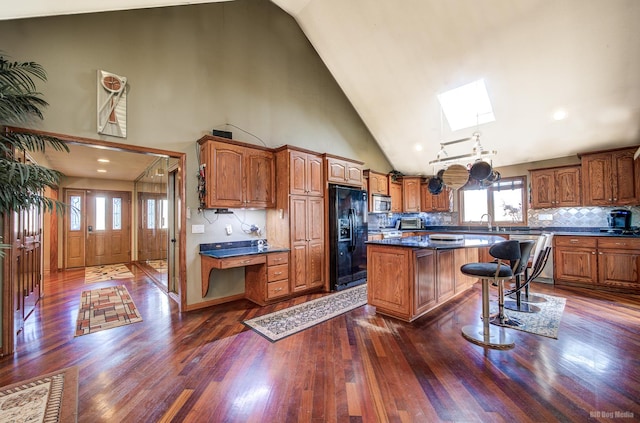 kitchen featuring backsplash, a skylight, stainless steel appliances, a center island, and high vaulted ceiling