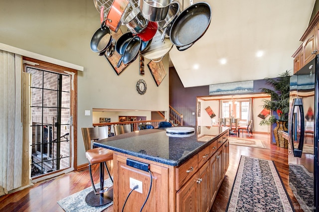 kitchen featuring black fridge, hardwood / wood-style floors, a kitchen island, french doors, and dark stone counters