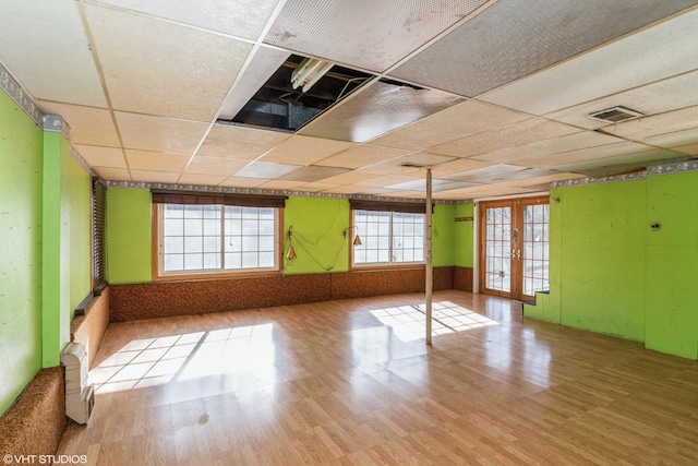 empty room with light hardwood / wood-style flooring, a paneled ceiling, and french doors