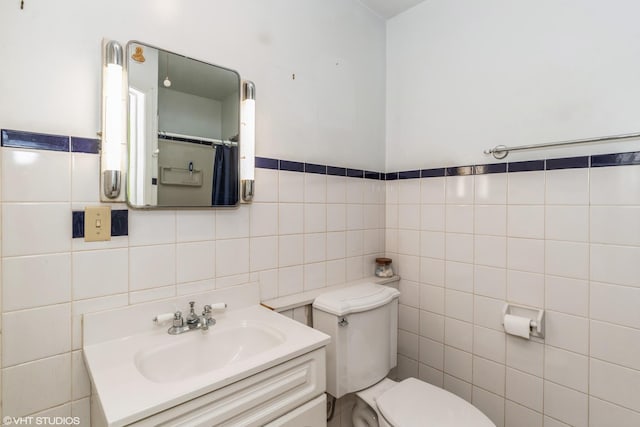 bathroom with tile walls, vanity, and toilet