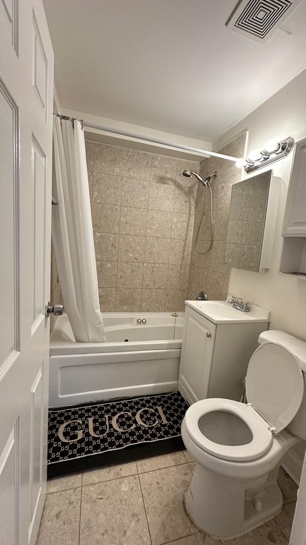 full bathroom featuring toilet, tile patterned floors, vanity, and shower / bath combo with shower curtain