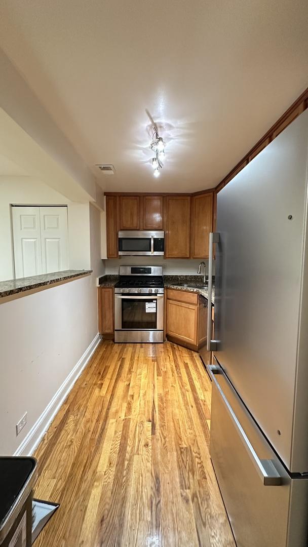 kitchen with light hardwood / wood-style floors and appliances with stainless steel finishes