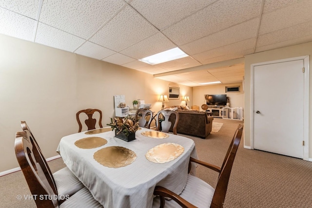 carpeted dining space featuring a paneled ceiling