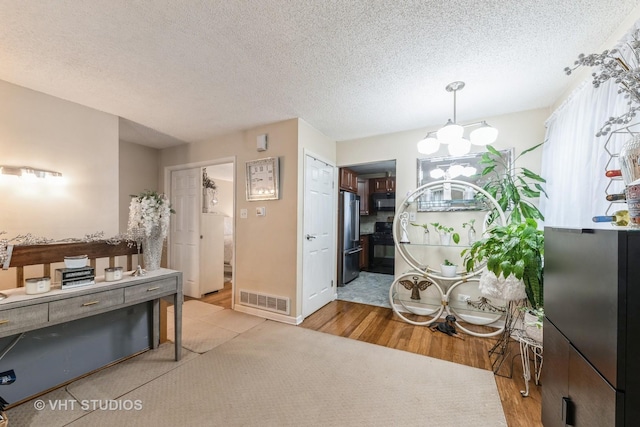 miscellaneous room with an inviting chandelier, hardwood / wood-style flooring, and a textured ceiling