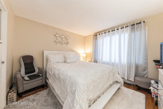 bedroom with dark hardwood / wood-style floors and a textured ceiling