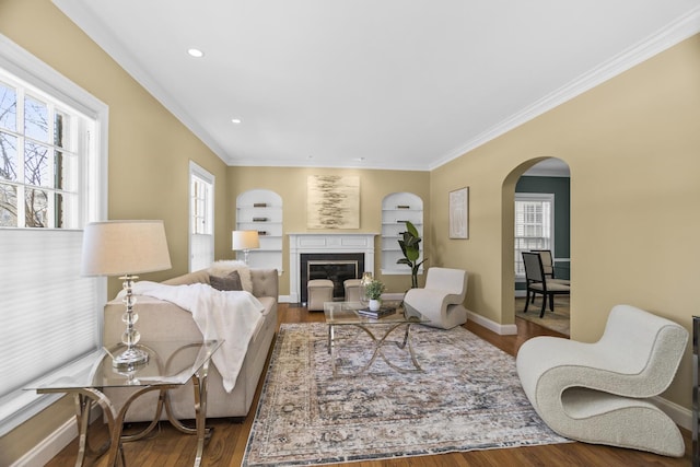 living room featuring hardwood / wood-style flooring, ornamental molding, and built in features