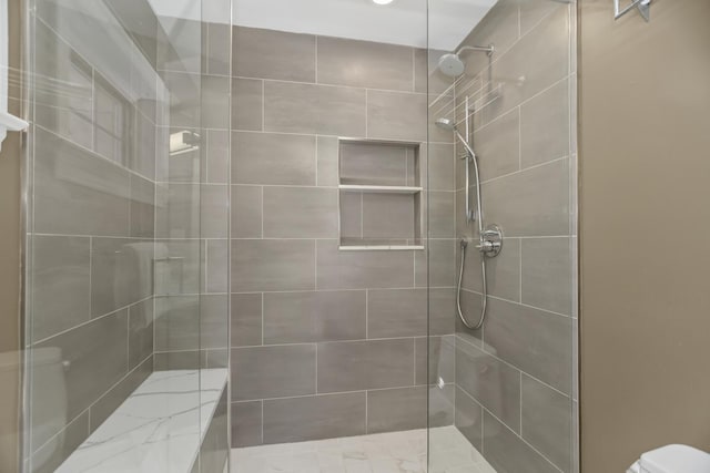 bathroom with a tile shower and toilet