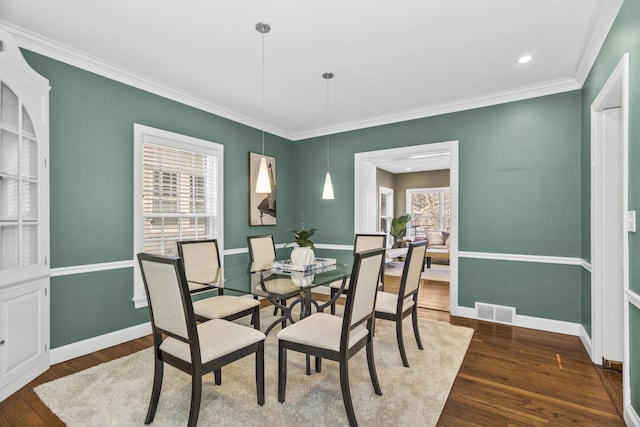 dining space with dark wood-type flooring, plenty of natural light, and ornamental molding