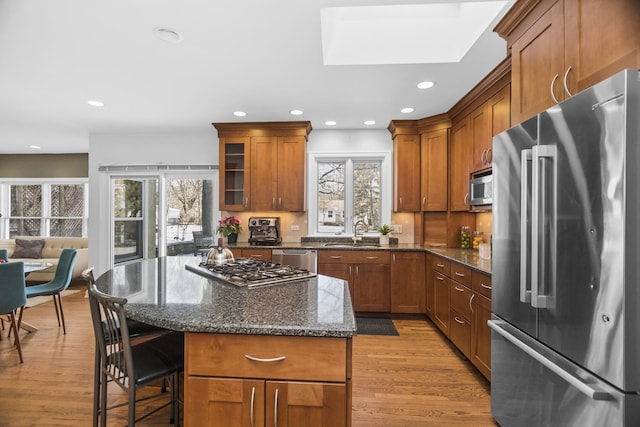 kitchen with dark stone countertops, stainless steel appliances, and a healthy amount of sunlight