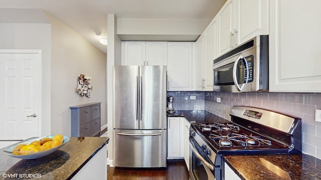 kitchen featuring white cabinets, stainless steel appliances, dark stone counters, and decorative backsplash