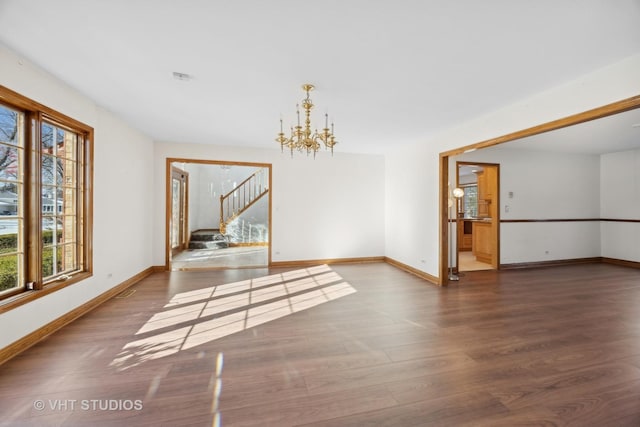 spare room with dark hardwood / wood-style flooring and a notable chandelier