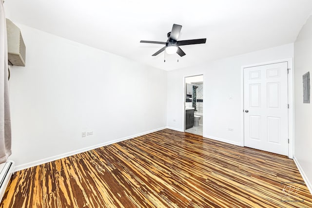 unfurnished bedroom with ensuite bath, baseboard heating, a closet, dark wood-type flooring, and ceiling fan