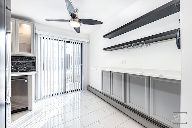 kitchen with gray cabinets, tasteful backsplash, light stone countertops, and a baseboard heating unit