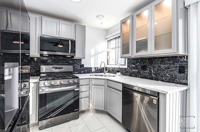 kitchen featuring light stone countertops, appliances with stainless steel finishes, tasteful backsplash, sink, and gray cabinets